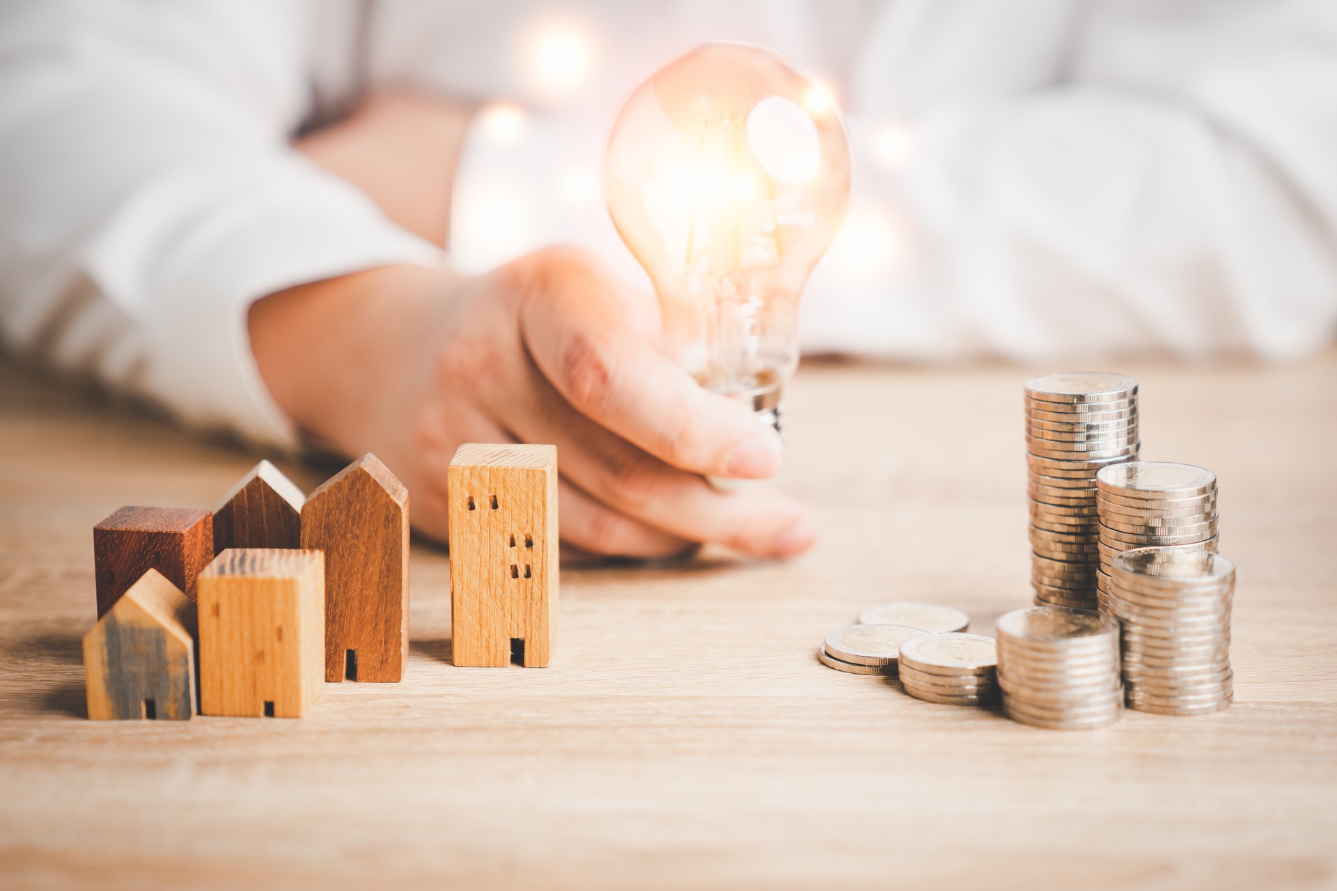 Wood house model and row of coin money with a man holding light bulb . Money management, financial plan, business idea and Creative ideas for saving money concept.